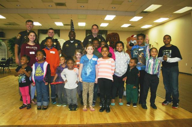 CCSO officers, McGruff the Crime Dog, and McGruff's nephew Scruff congratulate the winners of the 2014 National Night Out coloring contest.